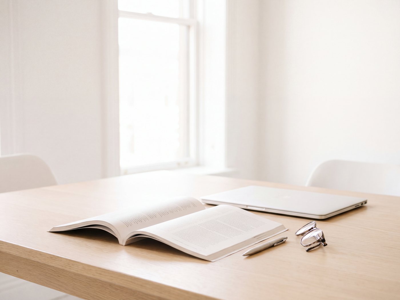 An open printed report beside a closed laptop on a pale meeting table in a bright room